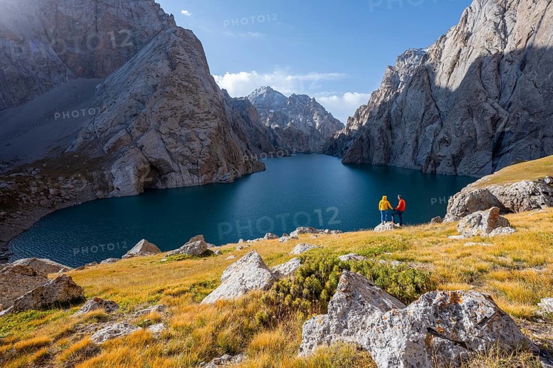 Tourists, couple at the blue mountain lake between rocky steep mountain peaks, Kol Suu Lake, Sary Beles Mountains, Naryn Province, Kyrgyzstan, Asia