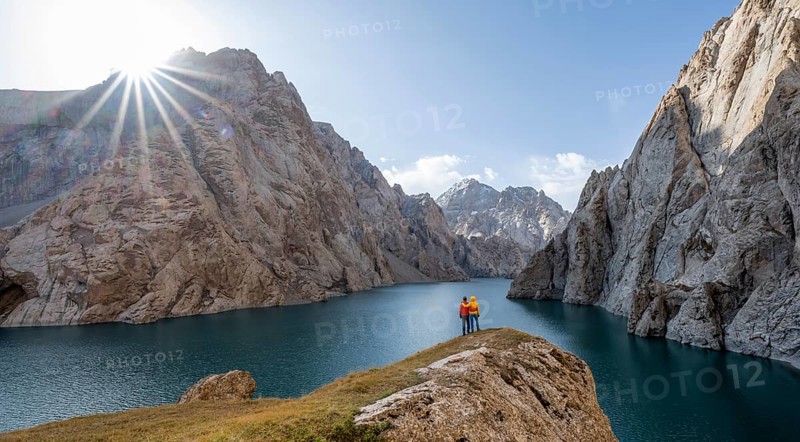 Couple at the blue mountain lake between rocky steep mountain peaks, Sun Star, Kol Suu Lake, Sary Beles Mountains, Naryn Province, Kyrgyzstan, Asia