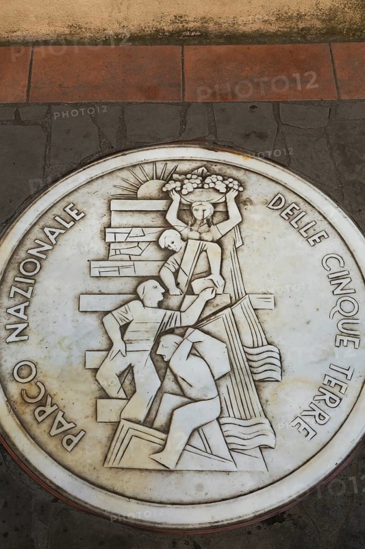 Round white marble plaque inscribed with the Italian words Parco Nazionale Delle Cinque Terre inlaid in paving stones, Manarola, Cinque Terre, La Spezia province, Italy, Europe