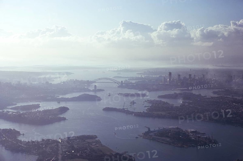 Oblique aerial view of the harbour, the bridge and the city centre skyline, Sydney, Australia 1974