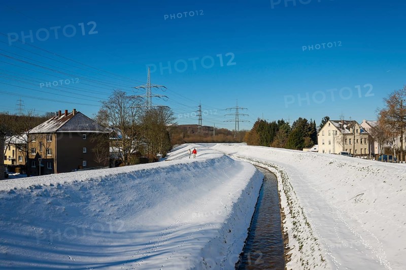 Bochum, North Rhine-Westphalia, Germany - Sunny winter landscape in the Ruhr area, ice and snow on the Hüller Bach, the stream is being transformed into a near-natural watercourse, is part of the Emscher river system and thus part of the Emscher conversion, is currently still partly an open, above-ground wastewater channel, mixed water channel with surface water and wastewater
