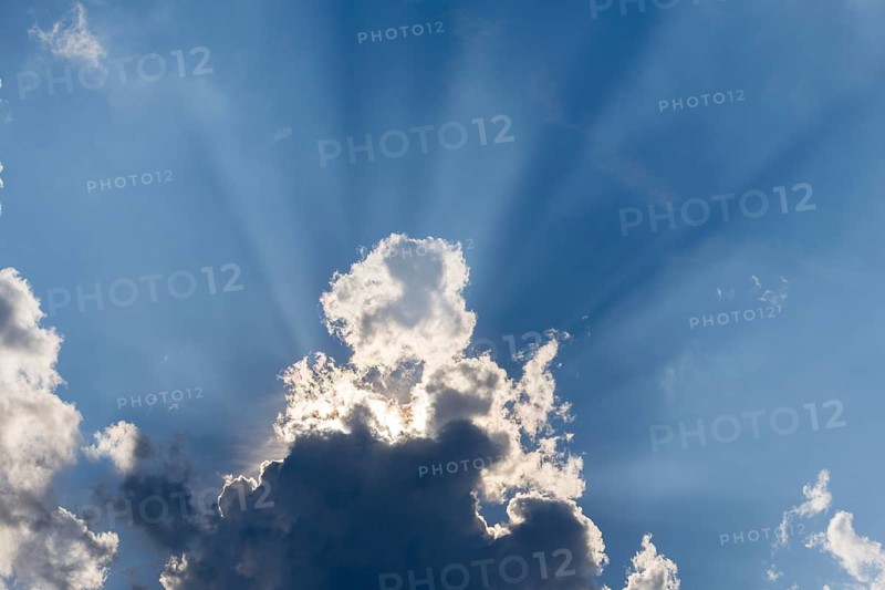Rain clouds with sun shining through, rays of sunshine, blue sky