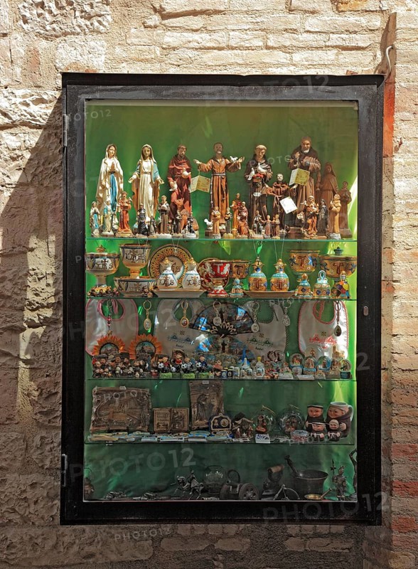 Shop window with figures of saints, devotional objects, in the historic centre of Assisi, Umbria, Italy, Europe