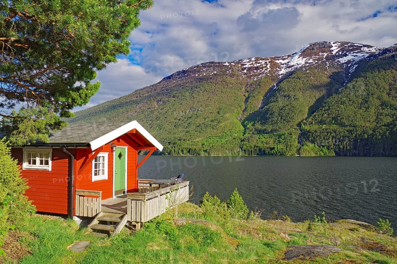 Red-painted cabin on the shore of a fjord against a backdrop of mountains and forest, holiday accommodation, Sognefjord, Sogndal, Norway, Europe