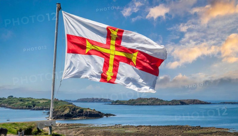 The flag of the Isle of Guernsey, Great Britain, flutters in the wind