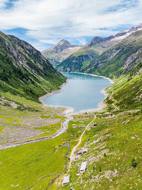 An alpine nature panorama with a mountain lake, green meadows, mountains, a river and a hiking trail under a cloudy sky, Klein Tibet, Zillertal, Austria, Europe