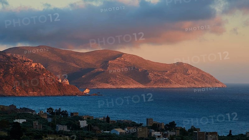A mountain landscape at dusk with a view of the sea and a small settlement in the foreground, Mani Peninsula, Peloponnese, Greece, Europe