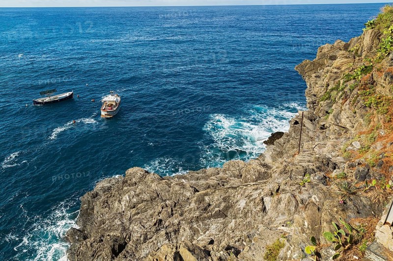 Rocky cliff and fishing boats moored in bay, Ligurian Sea, Manarola village in late summer, Cinque Terre, La Spezia province, Italy, Europe