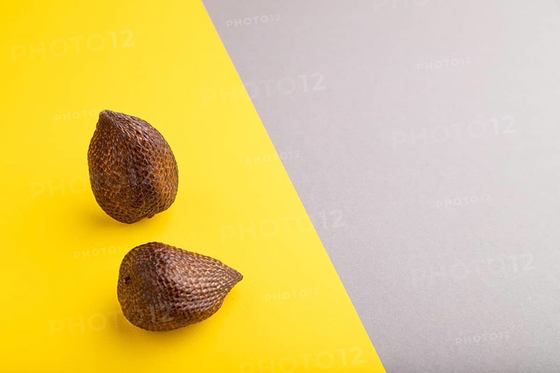 Salak or snake fruit on gray and yellow pastel background. Side view, copy space. Tropical, healthy food, summer, exotic, minimalism