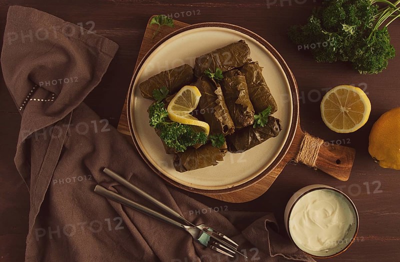 Dolma, cabbage rolls, grape leaves with filling, white sauce, lemon and herbs, rustic, selective focus, no people