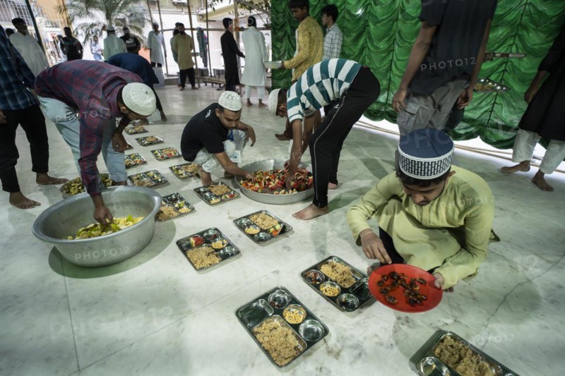 Volunteers distribute and arrange rows of 'iftar' meal for devotees to break their fast, during the holy month of Ramadan, at Burha Jame Masjid, on March 13, 2024 in Guwahati, Assam, India, Asia