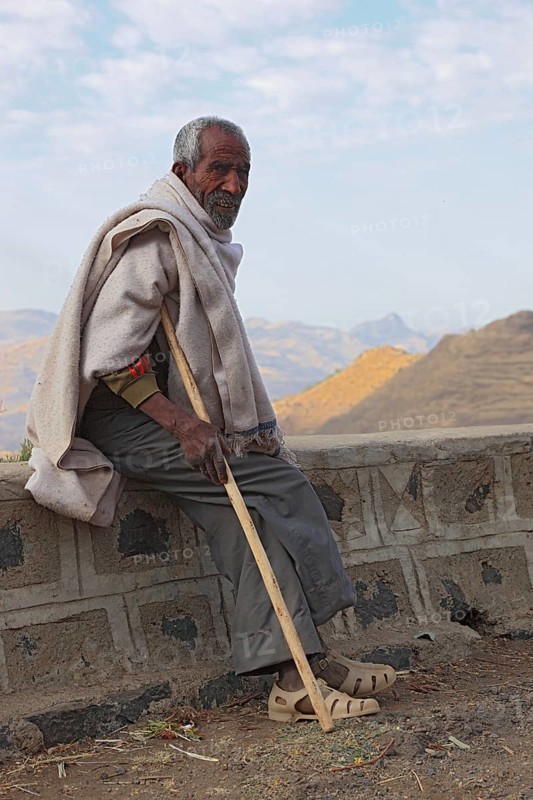 In the highlands between Mekele and Lalibela, elderly man with stick waiting by the road, Ethiopia, Africa