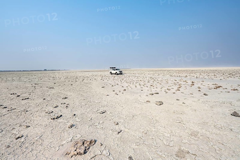 Four-wheel drive Toyota Hilux with roof tent, driving over salt pan, lone car in large wide plain, Nxai Pan National Park, Botswana, Africa