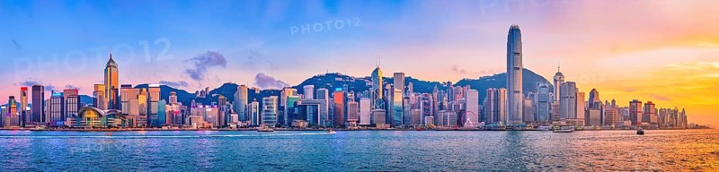 Panorama of Hong Kong skyline cityscape downtown skyscrapers over Victoria Harbour in the evening with junk tourist ferry boat on sunset with dramatic sky. Hong Kong, China, Asia