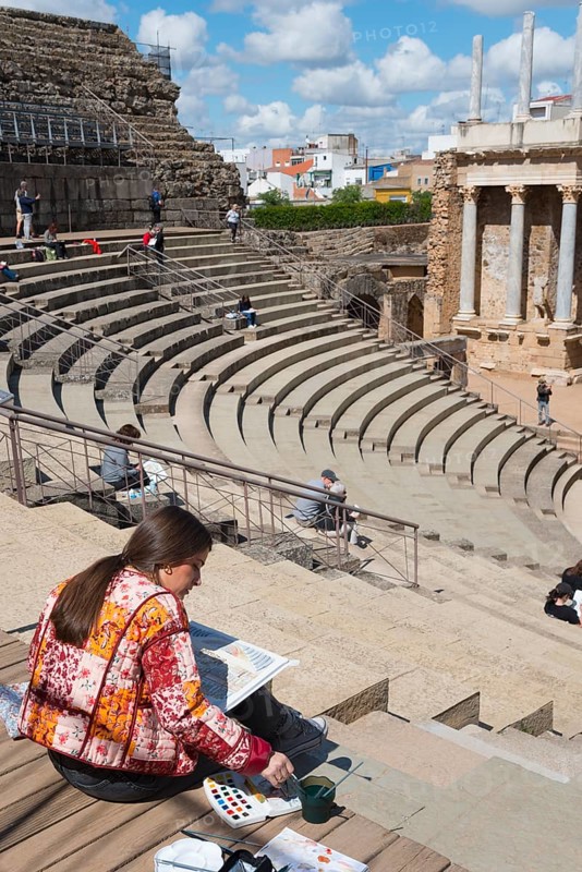 Woman painting a Roman theatre outdoors on a historical site, surrounded by stairs under a blue sky, Teatro Romano de Mérida, Roman Theatre of Merida, Merida, Badajoz, Extremadura, Spain, UNESCO World Heritage Site, Europe