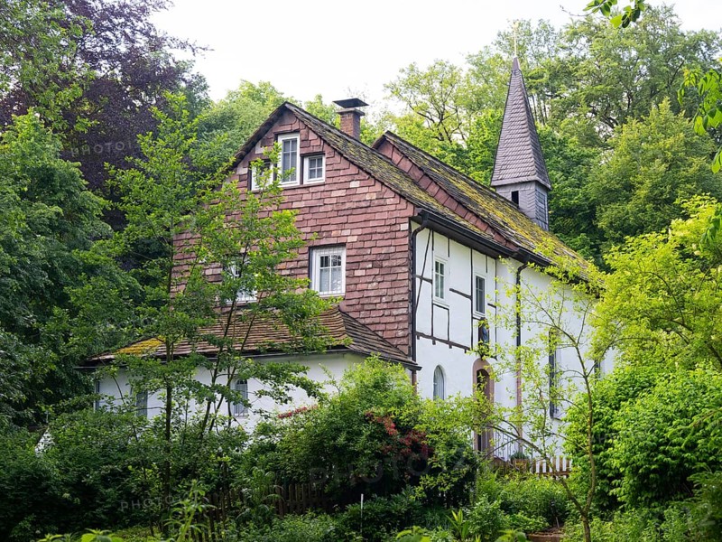 Klus Eddessen and vicar's house, an ancient pilgrimage site dating from 1856, situated in the middle of a wood, surrounded by fresh greenery in spring. The site is adorned with religious artifacts, situated between Beverungen and Borgentraich, county of Hoexter, Northrhein Westfalia, Germany, Europe
