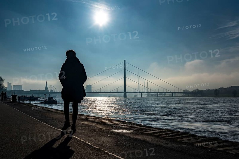 Dense fog is slowly lifting, riverside promenade on the Rhine near Düsseldorf, in front the Oberkassler Bridge, behind it the Rheinknie Bridge, North Rhine-Westphalia, Germany, Europe