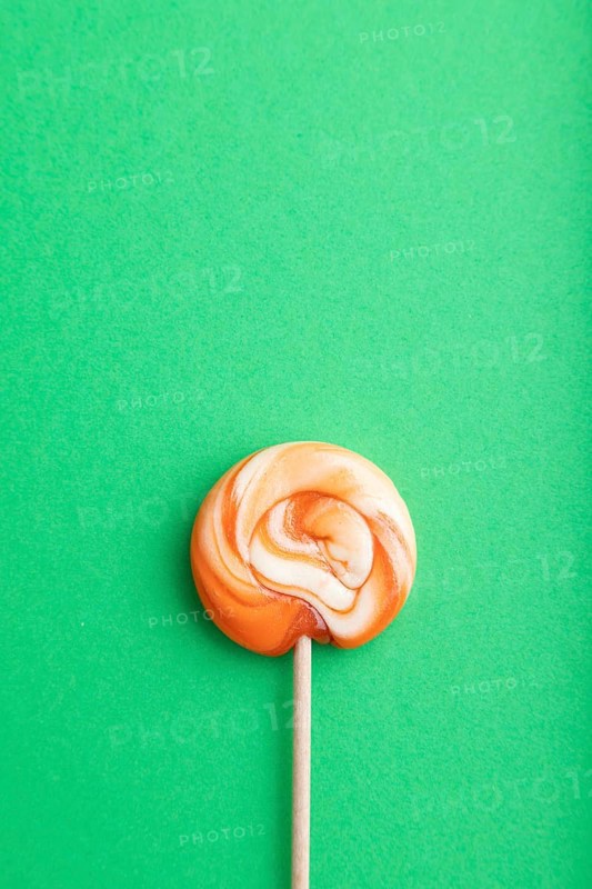 Single lollipop candy on green pastel background. copy space, top view, flat lay