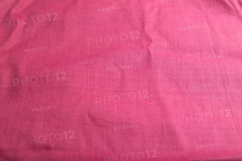 Fragment of smooth cotton purple tissue. Side view, natural textile background and texture