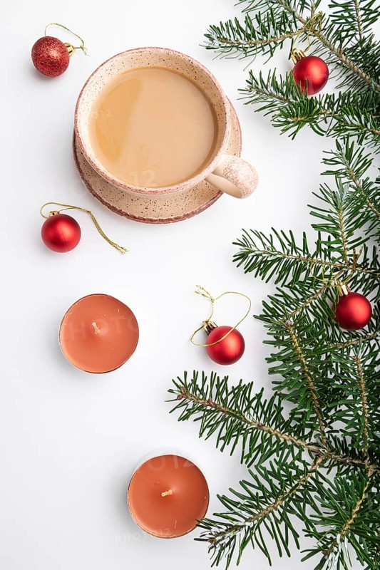 Christmas or New Year composition. Decorations, red balls, fir and spruce branches, cup of coffee, candles on a white paper background. Top view, close up, flat lay