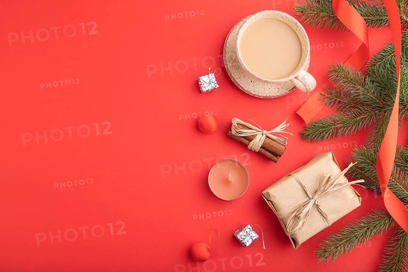 Christmas or New Year composition. Decorations, box, cinnamon, fir and spruce branches, cup of coffee, on a red paper background. Top view, copy space, flat lay