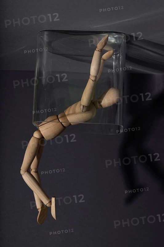 Wooden mannequin in a glass cube on gray background. captivity, break rules, loneliness, depression disorder concept. copy space