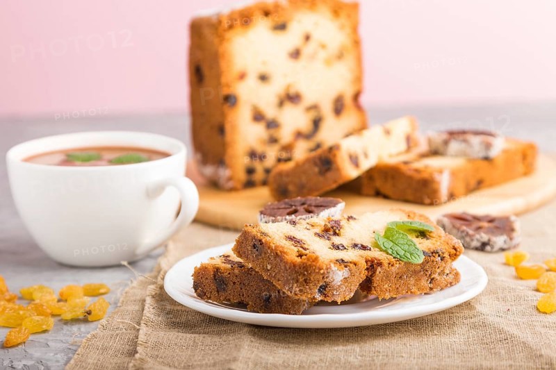 Homemade cake with raisins, dried persimmon and a cup of hot chocolate on a gray concrete background and linen textile. Side view, close up, selective focus
