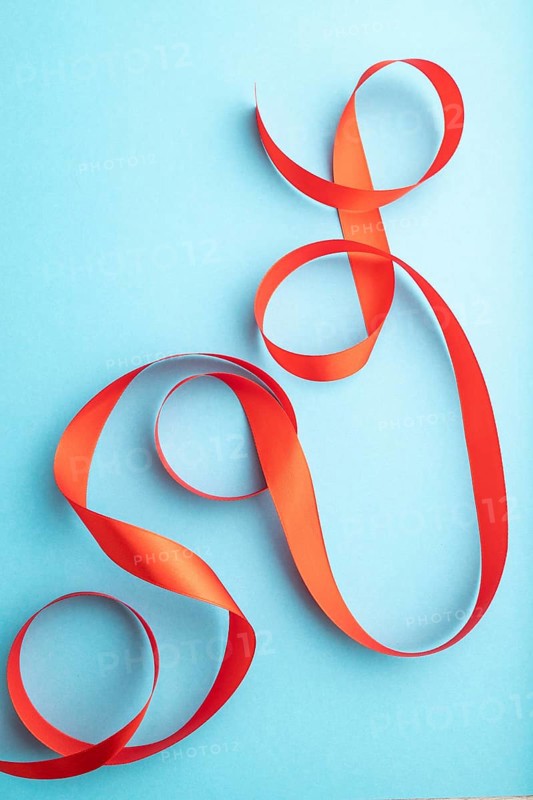 Red coral ribbon on a blue pastel background. Celebration concept. Top view, close up, flat lay