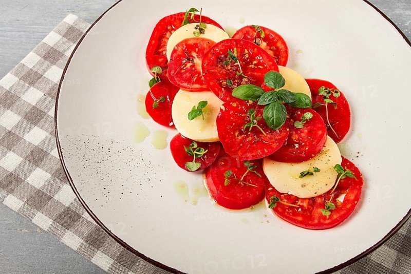Caprese salad, Italian traditional dish, tomatoes with mozzarella cheese, basil and spices, top view, no people