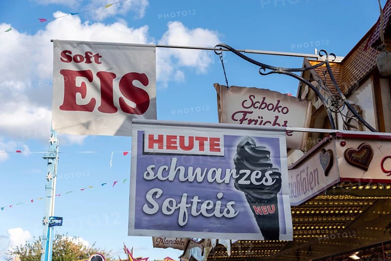 Advertising sign for black soft ice cream on a fairground with blue sky in the background, Magdeburg, Saxony-Anhalt, Germany, Europe