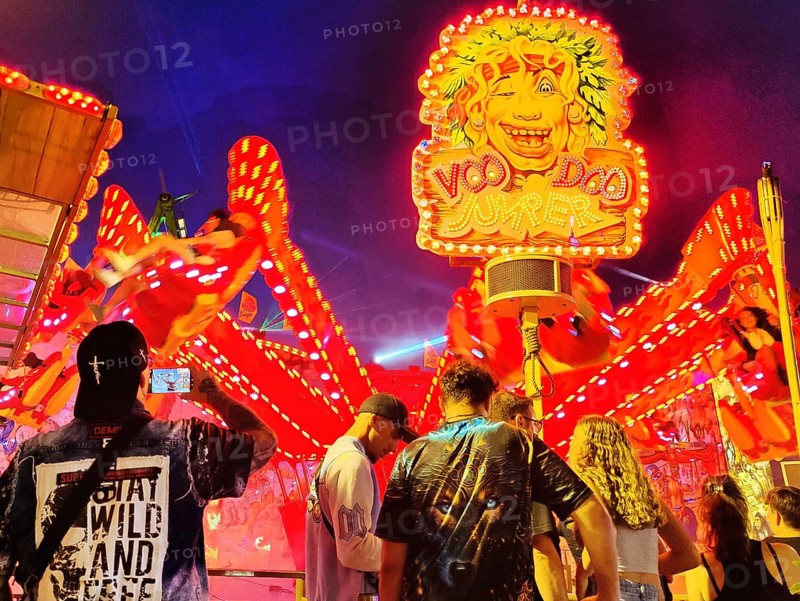 People in front of the illuminated carousel Voodoo Jumper at night, Cranger Kirmes, Herne, Ruhr area, North Rhine-Westphalia, Germany, Europe
