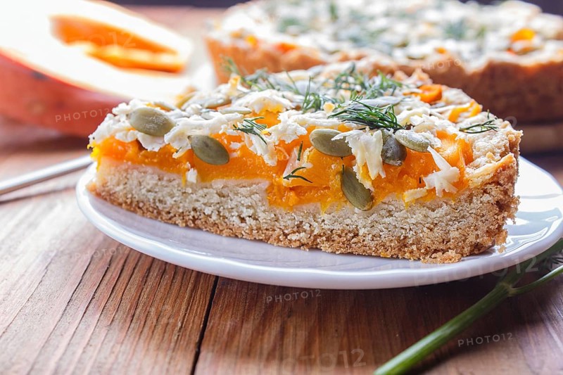 A piece of sweet pumpkin pie with cheese and dill on brown wooden background. close up