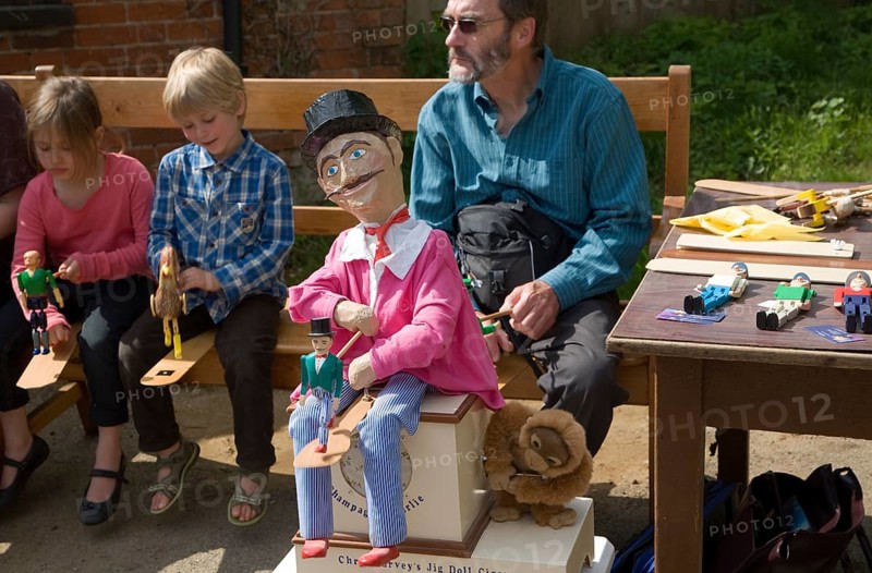 Man and children operating a traditional wooden jig doll dancer during a country folk event at Shottisham, Suffolk, England, United Kingdom, Europe