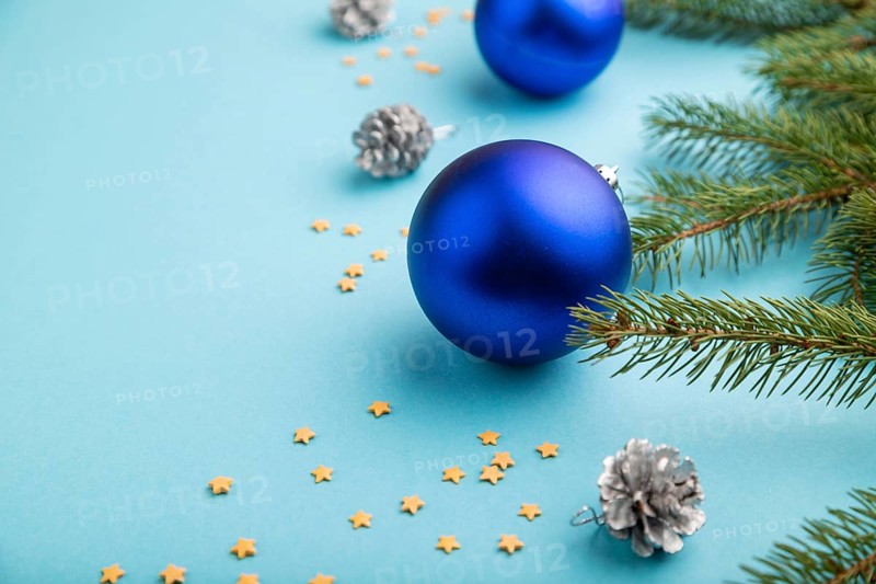 Christmas or New Year composition. Decorations, blue balls, cones, fir and spruce branches, on a blue paper background. Side view, copy space