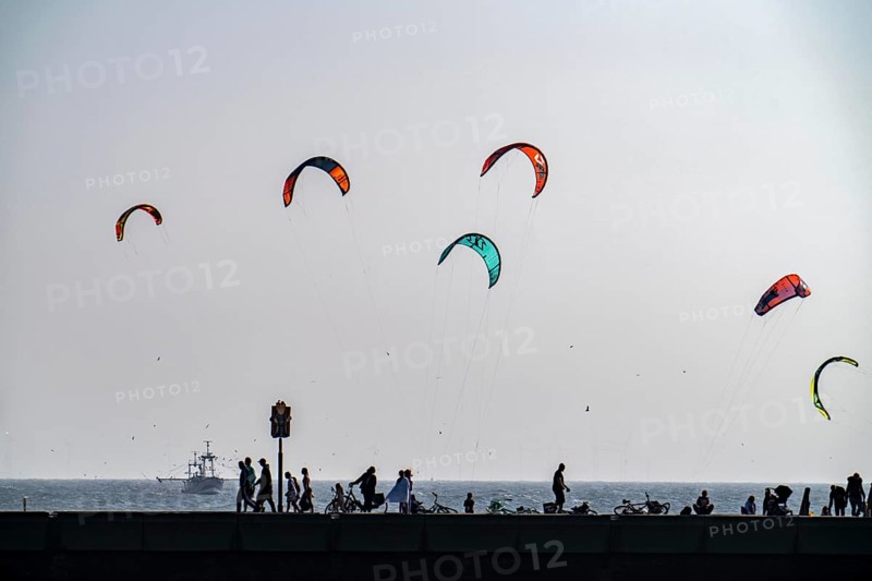 Kitesurfer off the coast of Scheveningen, walkers on the harbour pier, The Hague, Netherlands