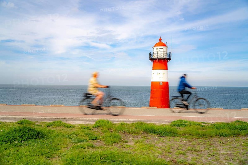 North Sea dyke near Westkapelle, Westkapelle Laag lighthouse, cyclists on the Zeeuwse Wind Route cycle path, province of Zeeland, Walcheren peninsula, Netherlands