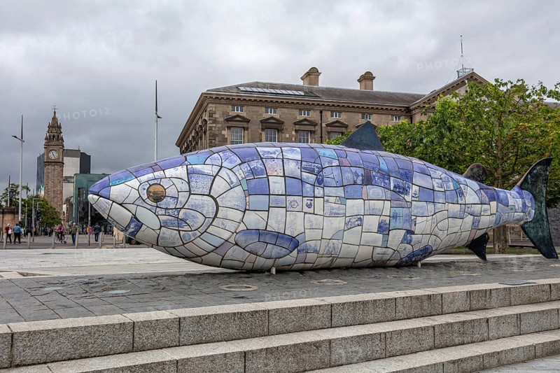 Colourful fish sculpture made of tiles in a public square in front of a historic building, Belfast