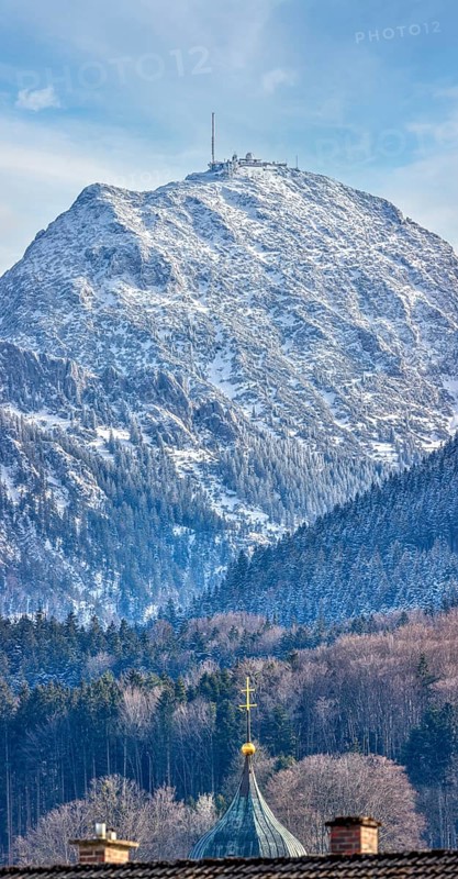 Snow-covered mountain with a church in the foreground under a clear blue sky, Bad Feilnbach Wendelstein