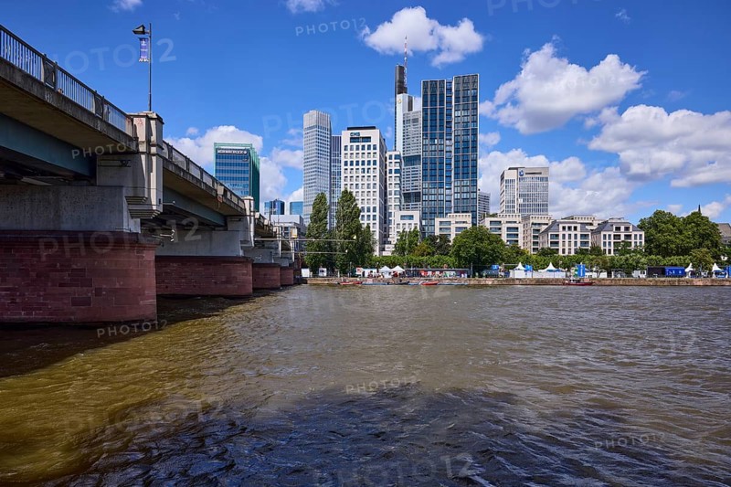 Skyscrapers and Untermainbrücke with Main river under blue sky with cumulus clouds in Frankfurt am Main, Hesse, Germany, Europe