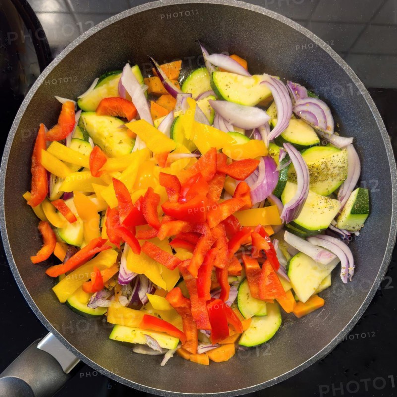 Vegetarian vegan dish Vegetable pan with courgettes red yellow peppers onions vegetable onions carrots carrots Vegetables are sautéed with olive oil in a Teflon-coated frying pan Teflon-coated frying pan, international