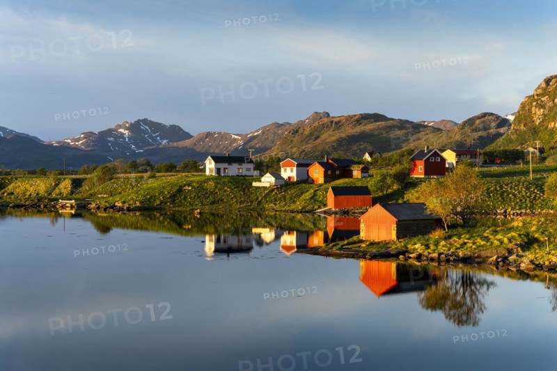 Landscape on the Lofoten Islands near Eggum. Houses on a fjord. At night at the time of the midnight sun in good weather, blue sky. Golden hour. Reflection. Early summer. Vestvagoya, Lofoten, Norway, Europe