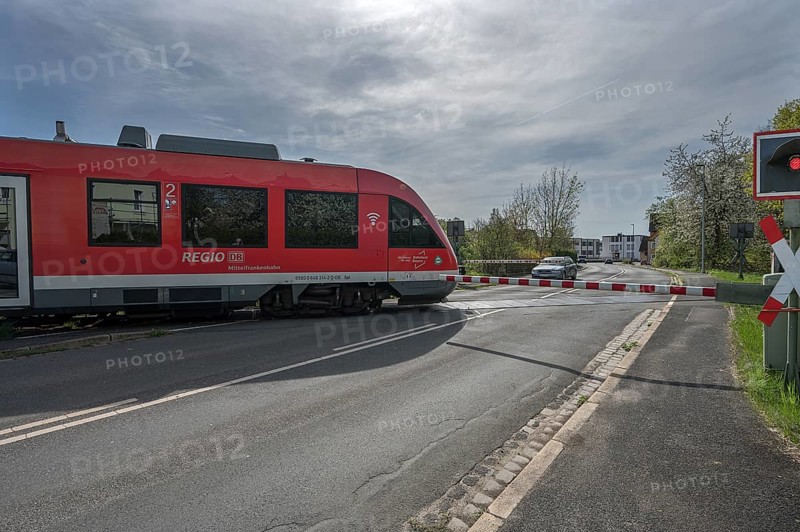A regional train crosses a level crossing with a barrier, Schnaittach, Middle Franconia, Bavaria, Germany, Europe