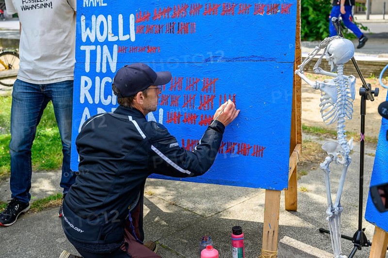 Richard Cluse marks the 60th day of his hunger strike on a large board. On the right, a skeleton clasping its hands over its head. Hunger strike camp, Invalidenpark, Berlin, 23 May 2024