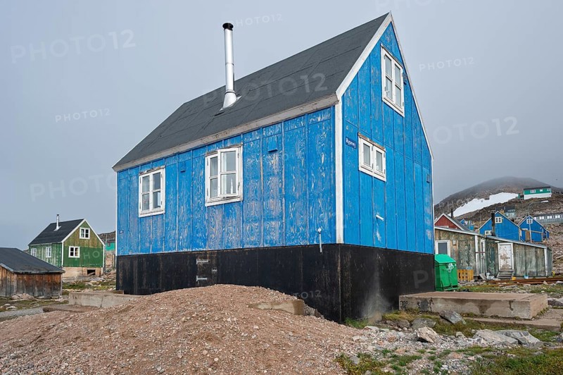 Blue house with chimney on rocky ground surrounded by colourful houses, remote Arctic Inuit settlement Ittoqqortoormiit, Scoresbysund or Scoresby Sund or Greenlandic Kangertittivaq, East Greenland, Greenland, North America