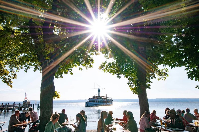 People in a beer garden under chestnut trees in Herrsching am Lake Ammer, in the background a steamer on the Lake Ammer, Bavaria, Germany, Europe