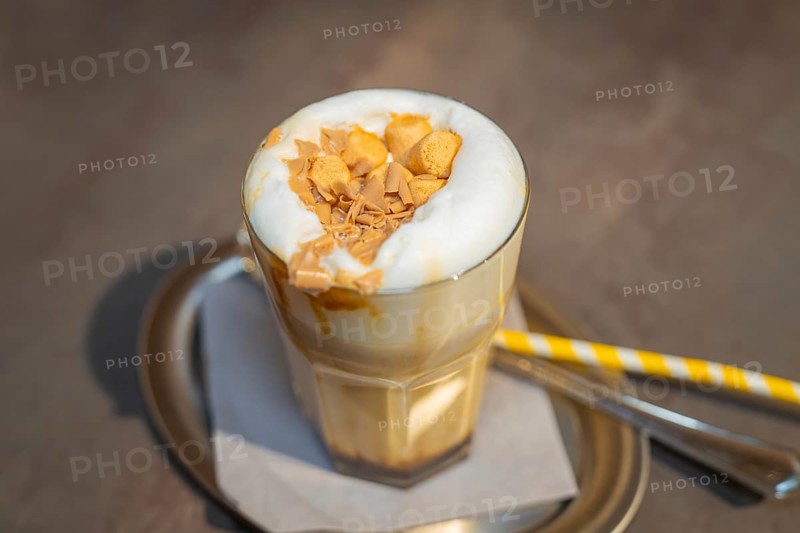 A glass of latte with creamy topping and biscuit crumbs on a serving tray, autumn creations, Cafe Kuh, Deckenpfronn, Black Forest, Germany, Europe