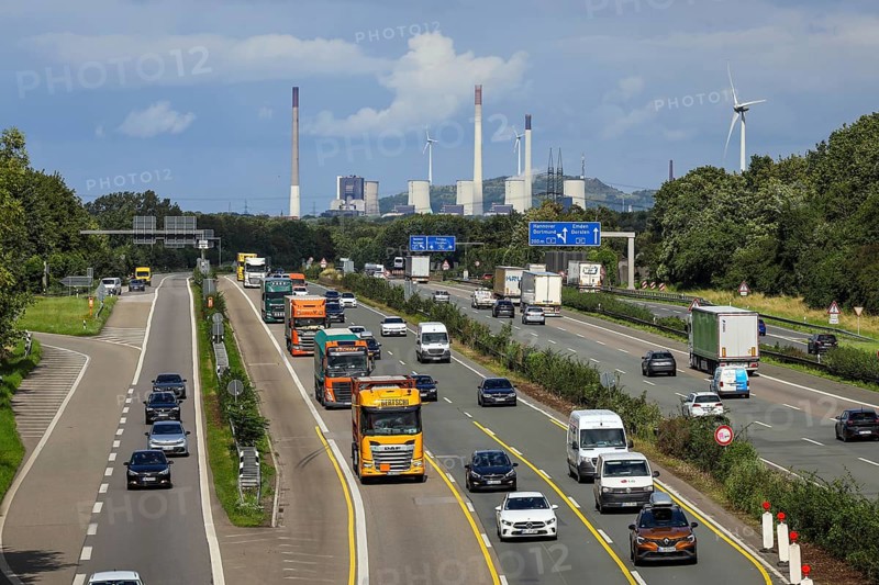 Bottrop, Ruhr area, North Rhine-Westphalia, Germany, rush hour traffic, many lorries driving on the A2 motorway, behind the Uniper coal-fired power plant Gelsenkirchen Scholven, on the right a wind turbine, industry and traffic in the Ruhr area, Europe