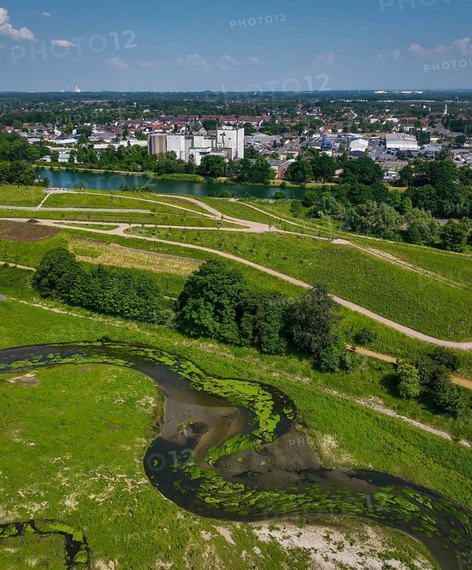 Castrop-Rauxel, Recklinghausen, North Rhine-Westphalia, Germany, EMSCHERLAND adventure park at the Emscher-RHK water crossing. View up the Emscher towards the future vineyard, the Rhine-Herne Canal and the industrial estate behind it. EMSCHERLAND, an approximately 30-hectare water and nature adventure park at the water crossroads of the Rhine-Herne Canal (rear) and the renaturalised Emscher (centre) on the border between Recklinghausen and Castrop-Rauxel. The ecological focus at the confluence of Suderwicher Bach (left) and Emscher (centre) will also be a future garden for the International Garden Exhibition 2027. Before the renaturation, the Emscher river system was an open, above-ground wastewater channel, a combined sewer with surface water and wastewater. Where the Emscher, the Suderwicher Bach and the Rhine-Herne Canal meet, an inter-municipal adventure park has been created in recent years on an area of around 30 hectares. The park's facilities include, Europe