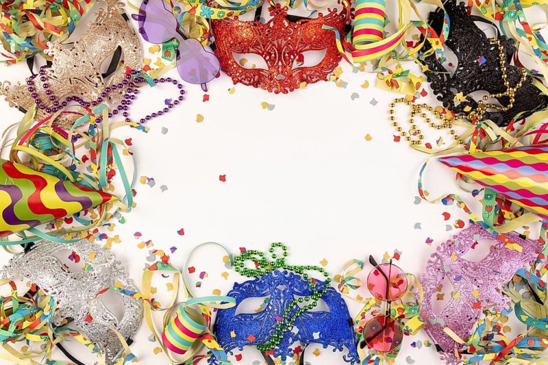 Colourful masks, paper streamers, confetti and party hats on a white background, carnival atmosphere
