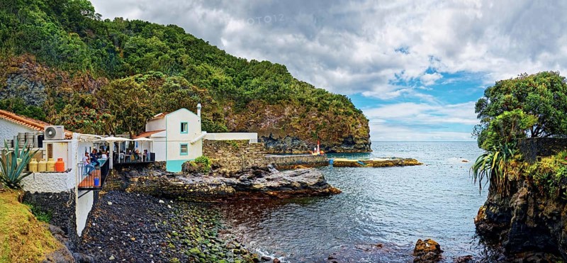Fish restaurant in the small fishing village of Caloura on the rocky coast with lush greenery and calm sea under a cloudy sky, Caloura, Ribeira Chã, Sao Miguel Island, Azores, Portugal, Europe